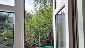 A view through a window with a metal fence and greenery outside. - DReAM Main Station (Kraków)