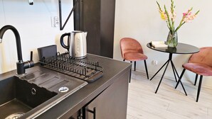 A compact kitchen with a sink, kettle, and a small dining area with a table and chairs. - DReAM Main Station (Kraków)