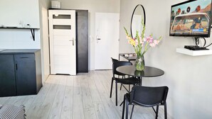 A modern kitchen with a white door, a dining area with a round table and chairs, and a TV mounted on the wall. - DReAM Main Station (Kraków)