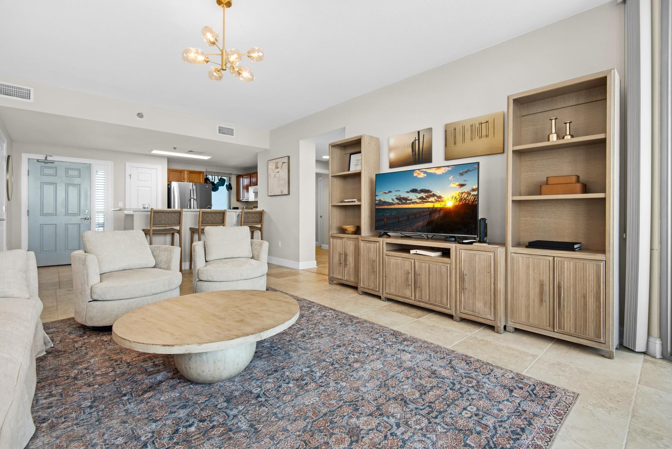 A spacious living room with a large TV, comfortable seating, and a decorative rug.
