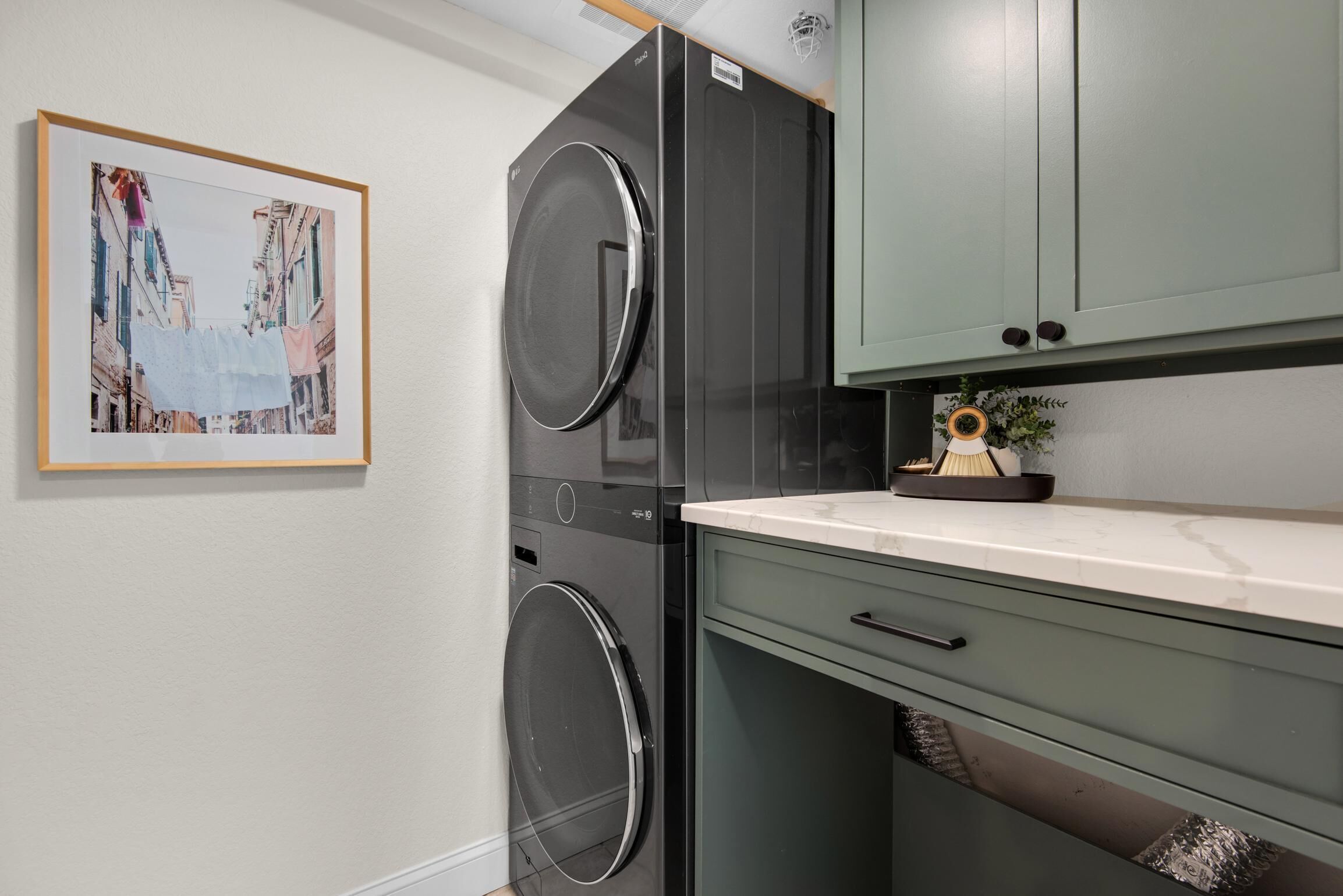 A compact kitchen with a built-in washer and dryer, a small countertop, and a cabinet with a decorative item.