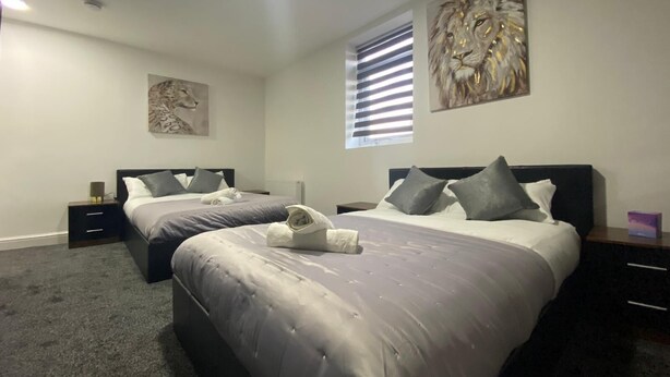 Een tweepersoonskamer met twee bedden, een groot raam met zonwering en kunst aan de wanden.