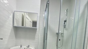 Een badkamer met een douchecabine, een wastafel op een zuil en een toilet.