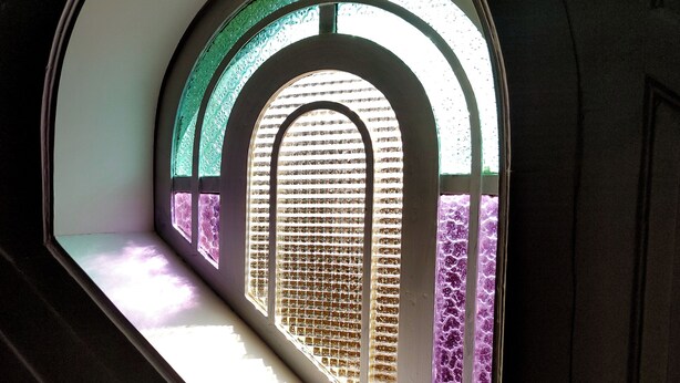 Ein Fenster mit Blick auf eine Ziegelwand und einen gemusterten Boden.