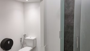 Ein modernes Badezimmer mit Toilette, Dusche und einer Duschkabine aus Glas.