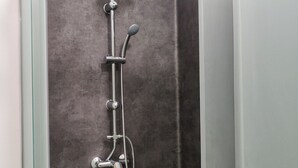 Eine Dusche mit Handbrause und Deckenbrause, vor einer Wand mit Struktur.