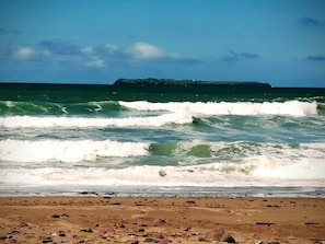 Ein Strand mit Wellen und einer entfernten Küste.