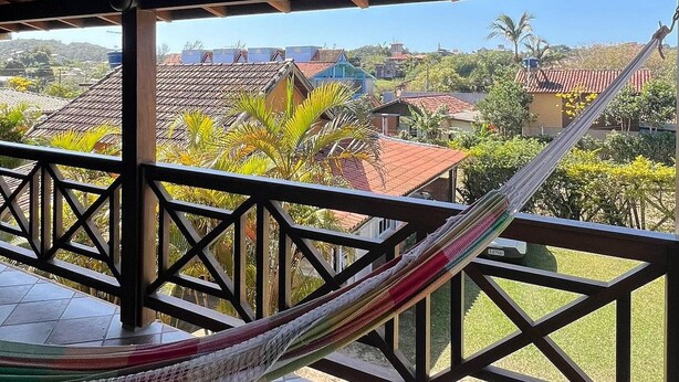 A hammock on a tiled balcony with a view of a residential area. - Pousada Recanto do Rosa (Imbituba)