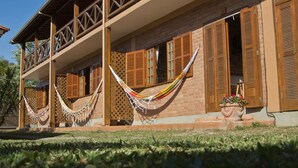 A two-story building with wooden balconies, a brick facade, and wooden shutters. - Pousada Recanto do Rosa (Imbituba)