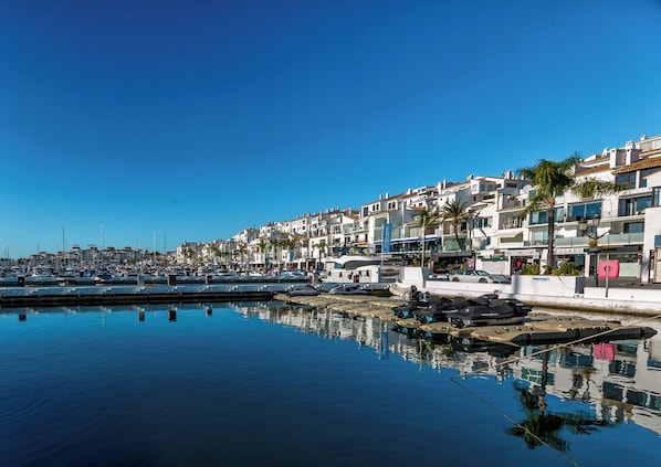 Marina com barcos e uma fileira de edifícios brancos com varandas.