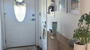 A hallway with a white door, a wooden cabinet, and a potted plant. - Lakeside home with Main Channel views (Sunrise Beach)