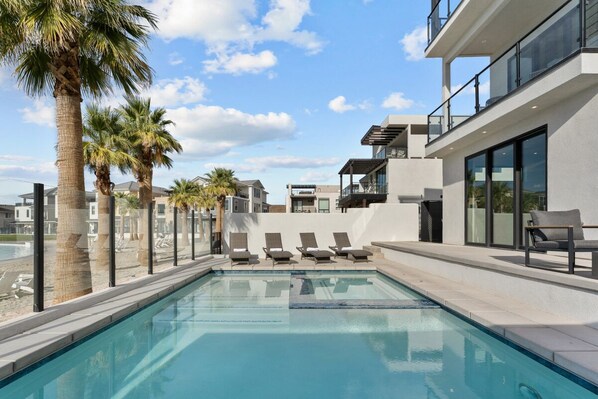 Relax by the pool surrounded by palm trees and lounge chairs.