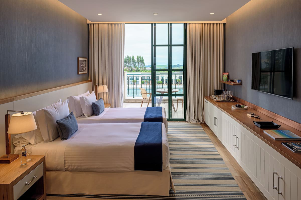 Hotelkamer met twee bedden, een televisie, een balkon met uitzicht en een minibar.