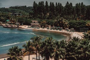 Um resort à beira-mar com área de piscina, espreguiçadeiras e uma torre de salva-vidas.