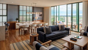 Una habitación de hotel moderna con comedor, sofá y balcón con vistas.