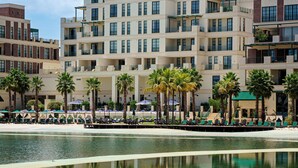 Un hotel moderno con varios balcones, zona de piscina y palmeras.
