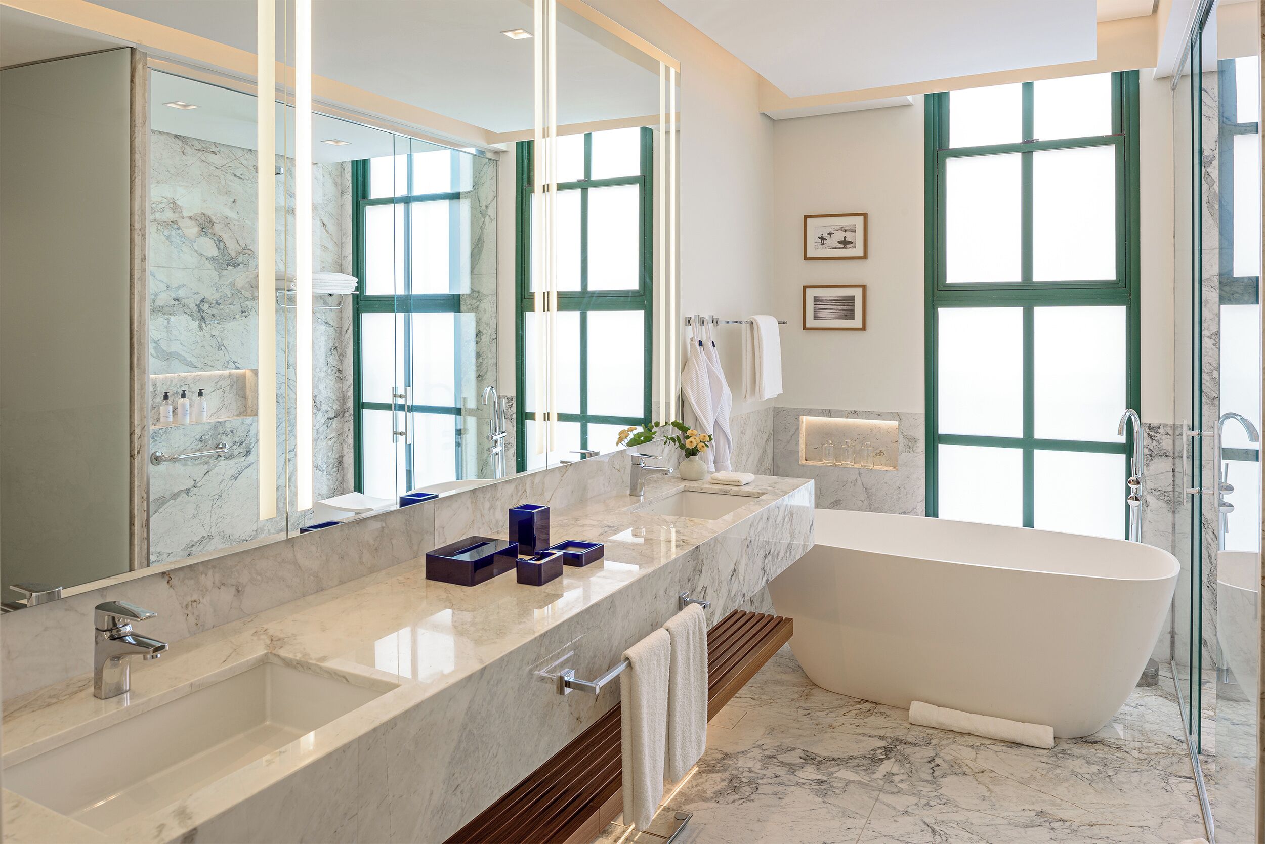 A modern bathroom with a freestanding bathtub, a large vanity with a marble countertop, and a large mirror.