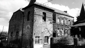 A historic building with a prominent tower and a brick facade. - Aux Deux Tours (Leval)