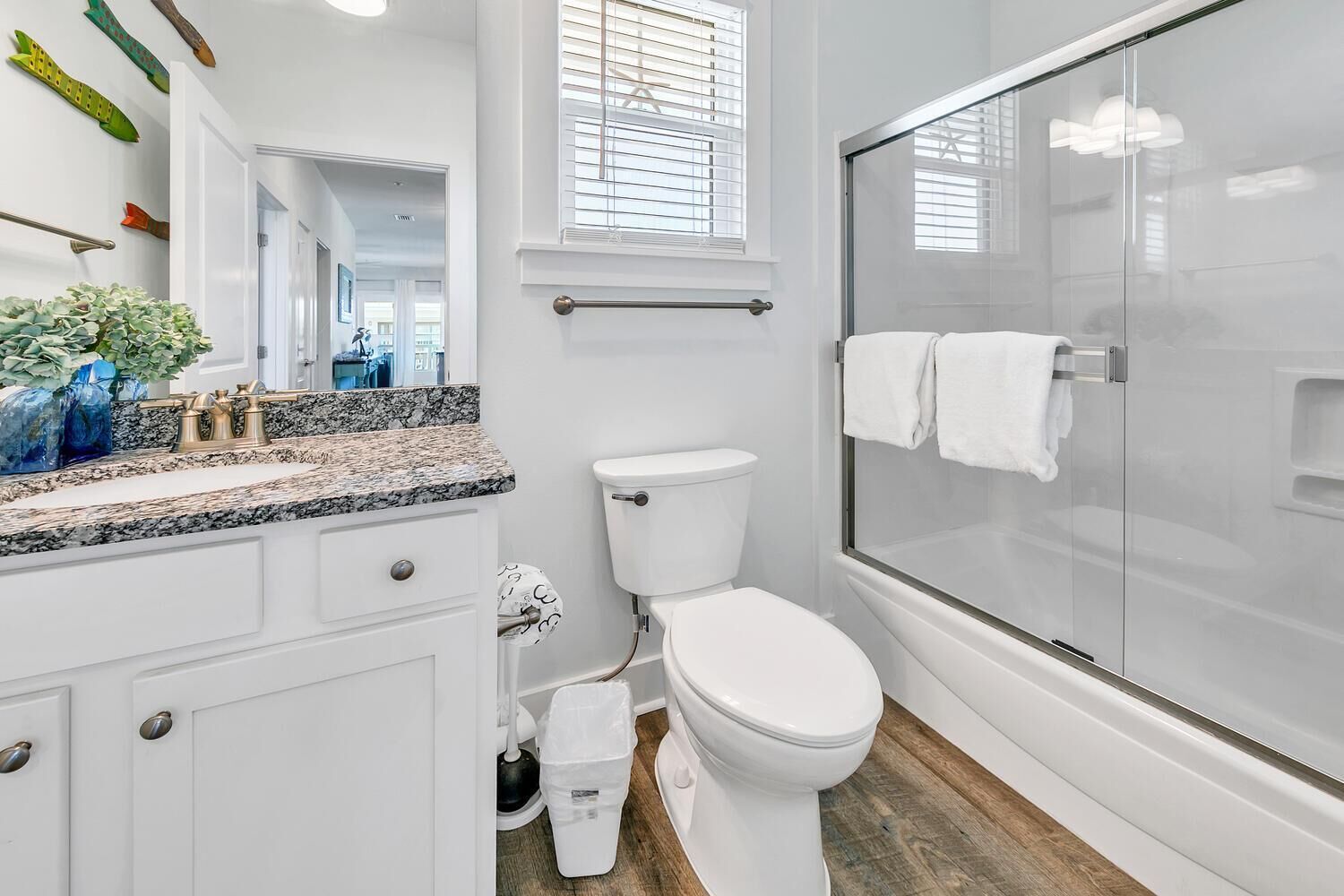 A modern bathroom with a white toilet, a glass-enclosed shower, and a granite countertop.