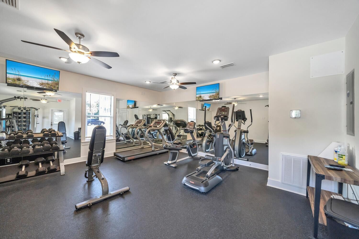 Une salle de sport équipée de tapis de course, de vélos elliptiques et de poids libres.
