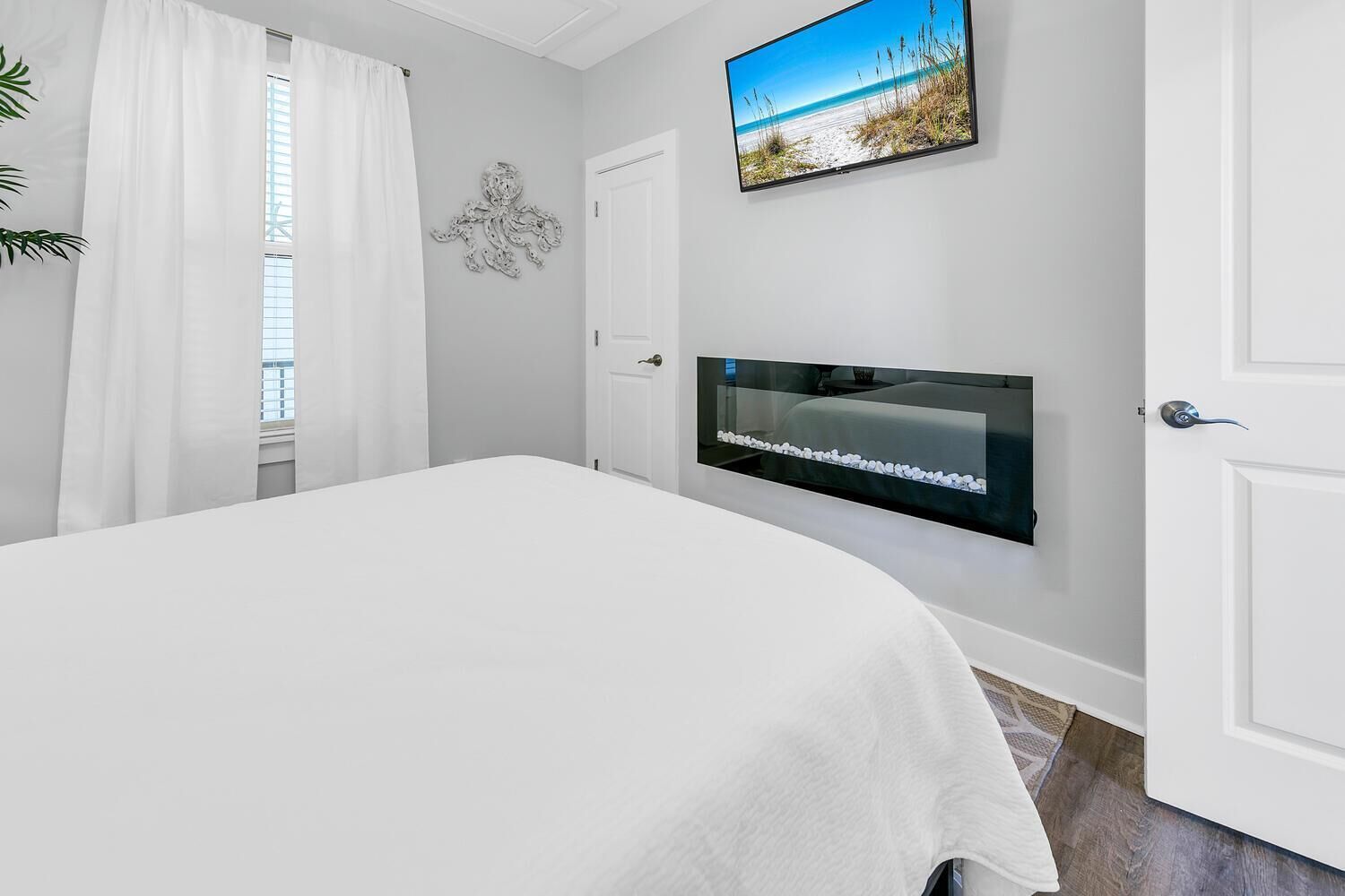 Une chambre à coucher avec un lit, un téléviseur fixé au mur et une porte.