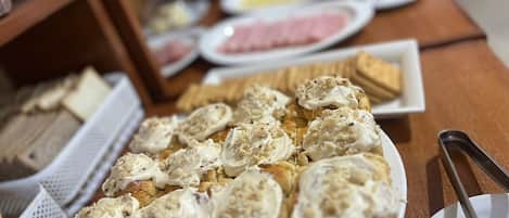 Egy svédasztal, melyen különféle ételek találhatók, többek között egy tányérnyi, tejszínnel és dióval töltött sütemény, valamint egyéb ételek.