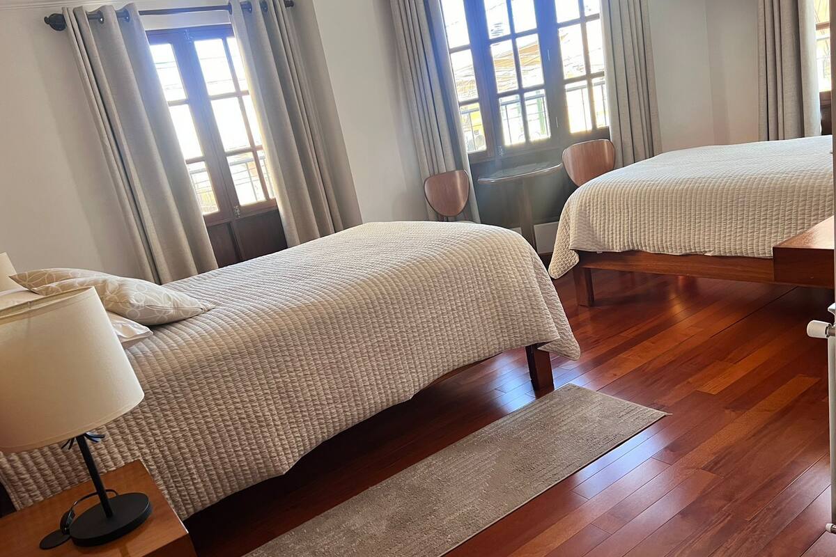 Habitación de hotel con dos camas, un escritorio y una ventana con cortinas.