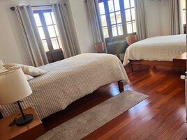 Habitación de hotel con dos camas, un escritorio y una ventana con cortinas.