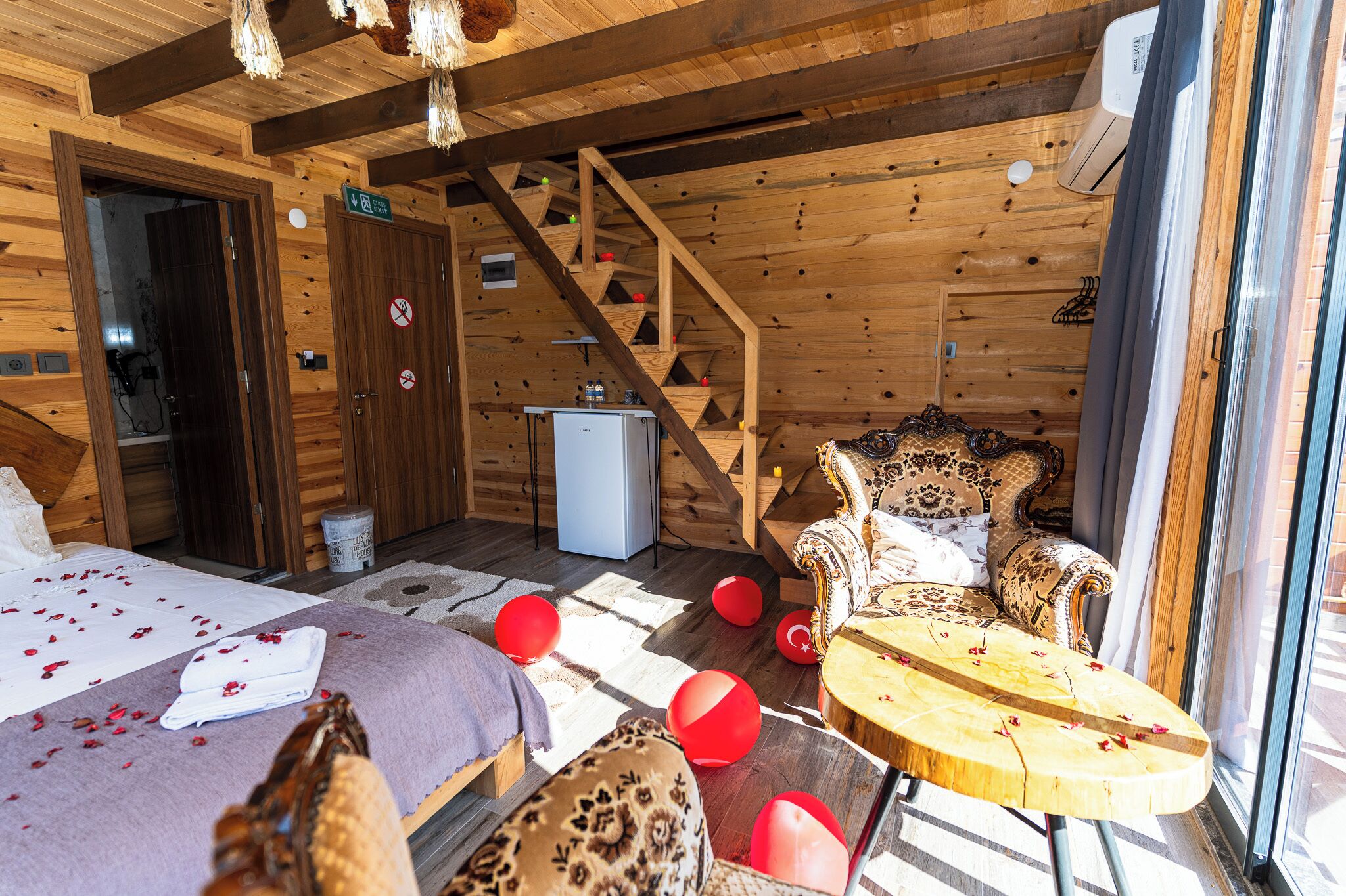 Uma cabana de madeira com cama, sofá, mesa e escada.