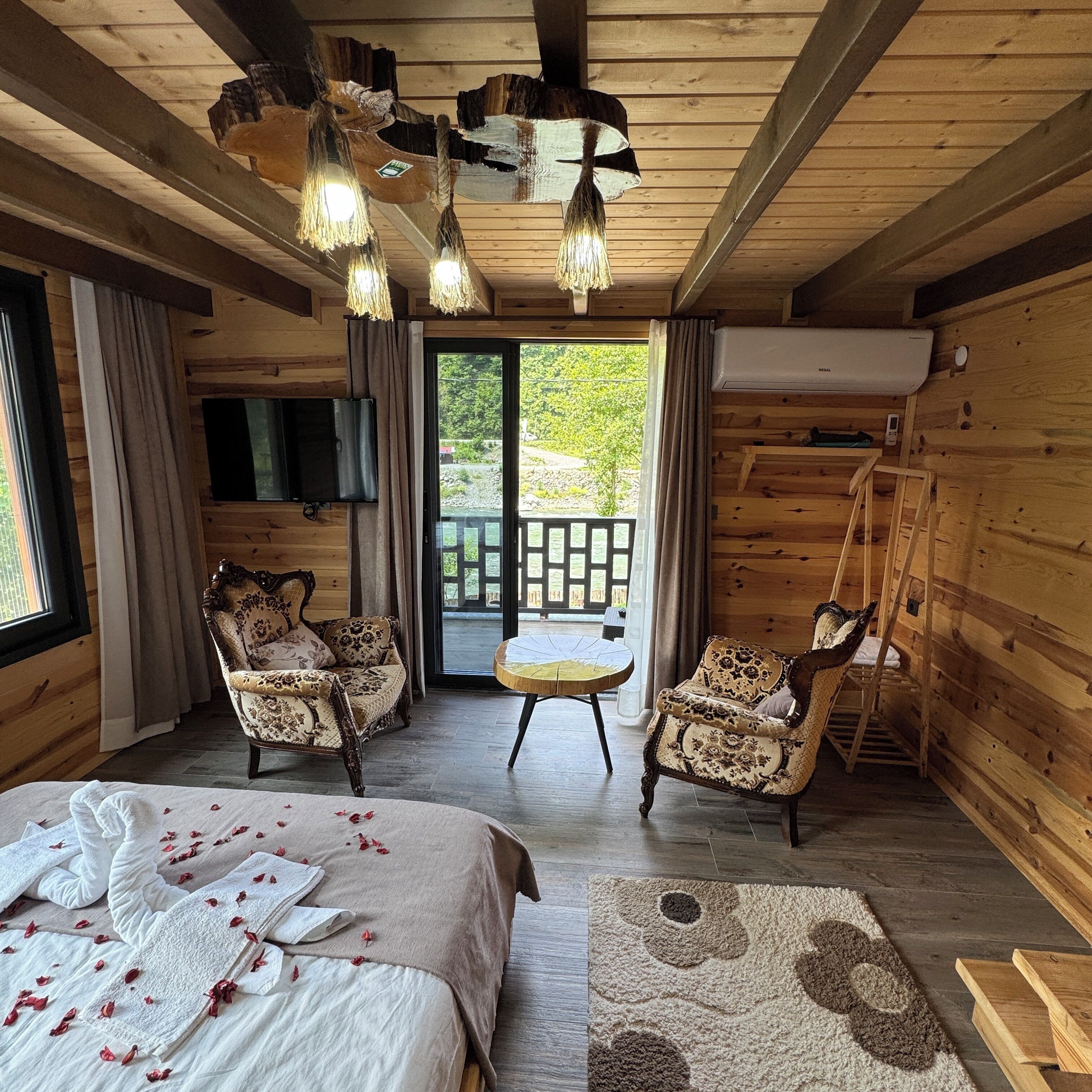 Accogliente camera in legno con un letto, due poltrone, un tavolino e vista sull'esterno.