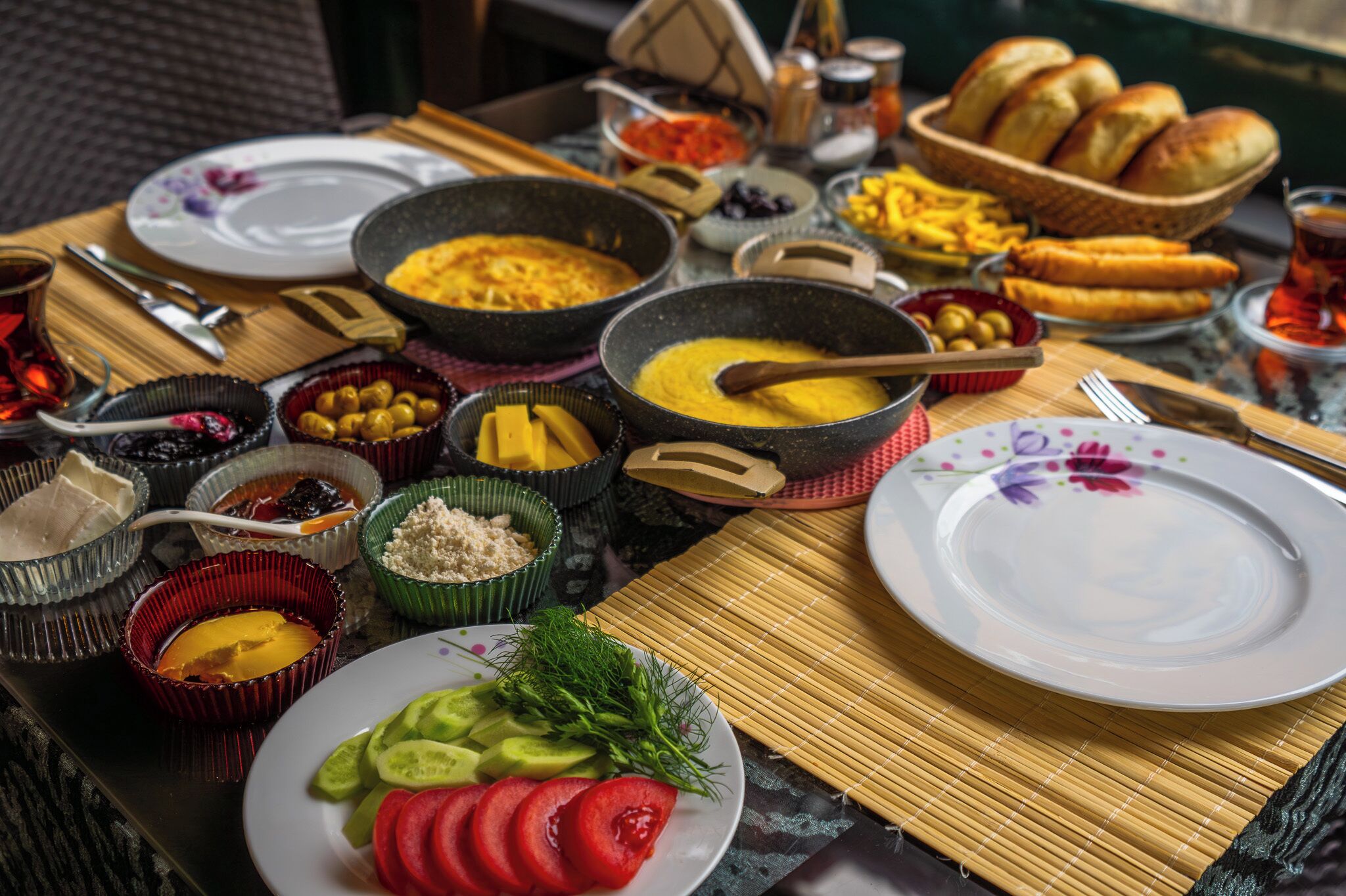 A table with various dishes and utensils, including bowls of food, plates, and a teapot.