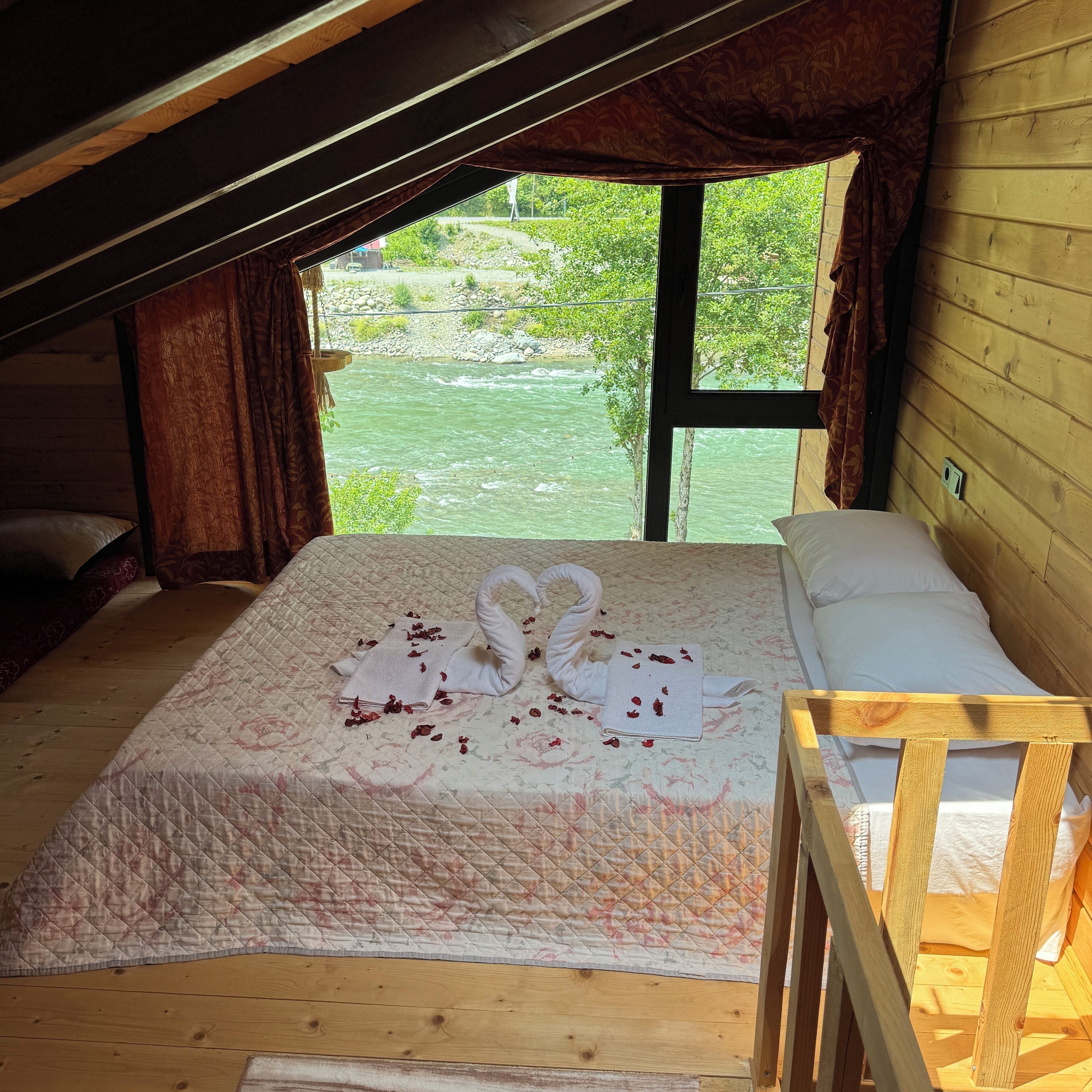 Een gezellig houten kamer met een bed, versierd met een zwaan van handdoeken en rozenblaadjes.