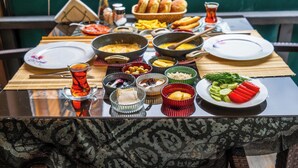 Una mesa con diversos platos y una taza de té, sobre una mesa de madera con vistas al exterior.