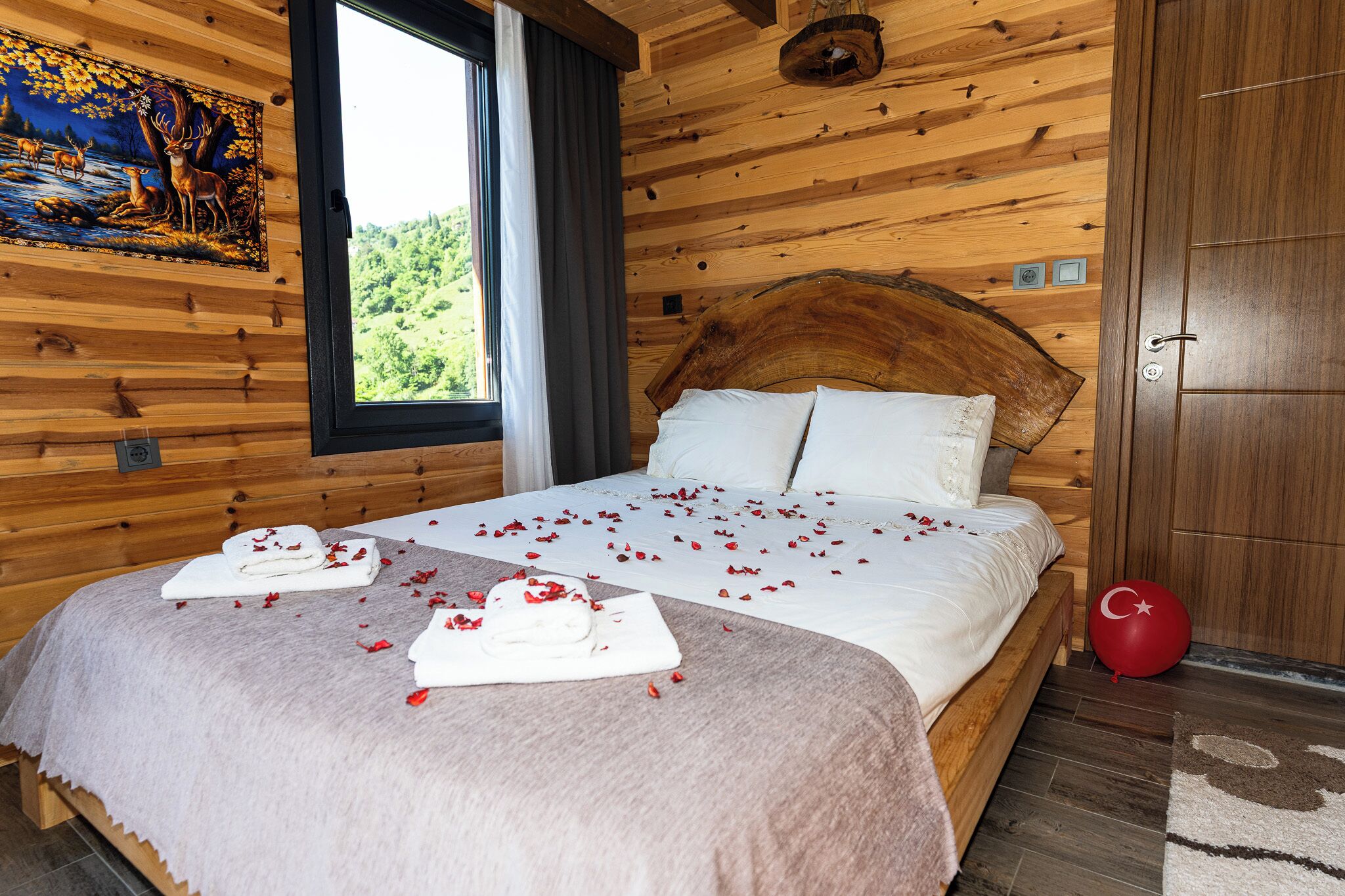A wooden cabin bedroom with a bed, a painting, and a window.