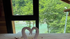 Una cama con una toalla dispuesta en forma de corazón y pétalos de rosa esparcidos.