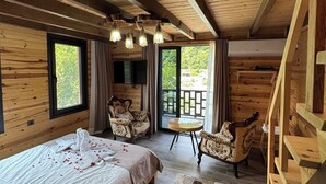 Una habitación de cabaña de madera con una cama, dos sillas, una mesita y una escalera.