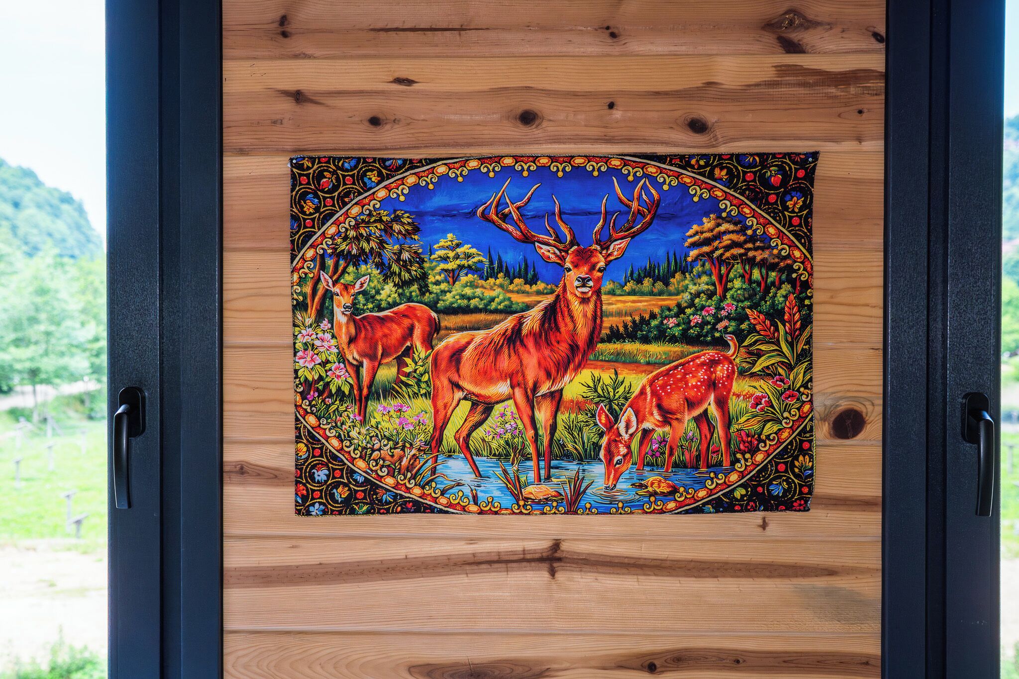 A framed painting of deer in a natural setting.