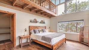 A bedroom with a wooden bed, a nightstand, a dresser, and a window with a view of trees. - Mountain Views 11br 20 People Jarabacoa (Jarabacoa)
