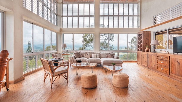 A spacious living area with large windows, a wooden floor, a sofa set, and a television. - Mountain Views 11br 20 People Jarabacoa (Jarabacoa)