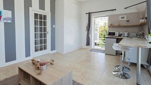 Una cocina moderna con armarios blancos, microondas integrado y un refrigerador pequeño.