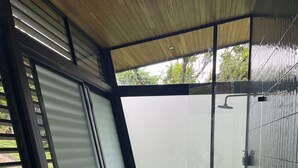 Un bagno moderno con una grande porta in vetro, una vasca freestanding e una zona doccia.