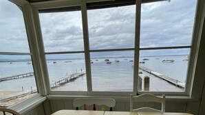 Een kamer met een groot raam met uitzicht op een waterpartij met boten en een steiger.
