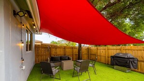 Ein Garten mit Kunstgrasanlage, Gartenmöbeln und einem Grill.