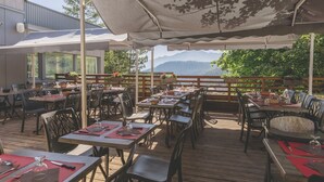 An outdoor dining area with tables and chairs, a wooden deck, and a view of mountains.