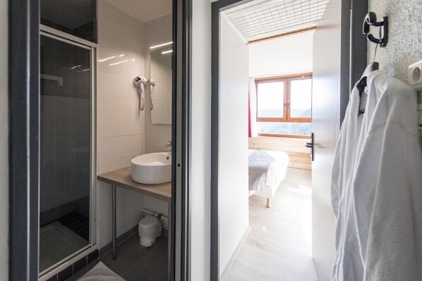 A modern bathroom with a glass shower enclosure, a white sink, and a wooden floor. - Club Vacances Bleues Arc-en-ciel - Ski Pass Inclus (Montricher-Albanne)