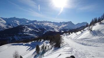 A snow-covered mountain landscape with a clear sky and a bright sun.