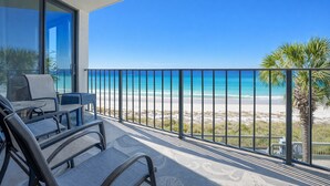 A balcony with a view of the beach and ocean.