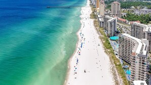 An aerial view of a beach with a pier extending into the ocean.