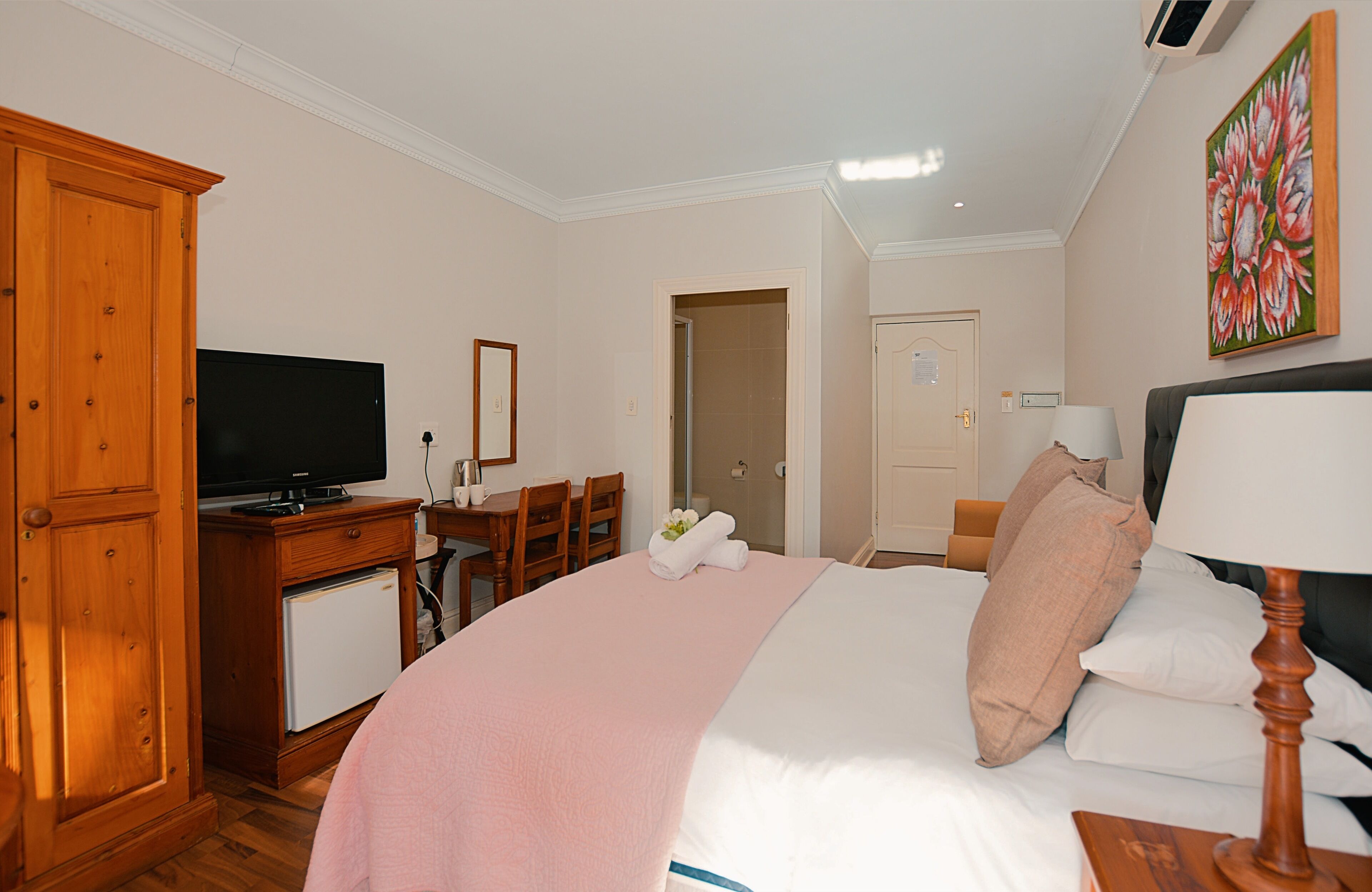 Une chambre d’hôtel avec un lit, une télévision, un bureau et une chaise.