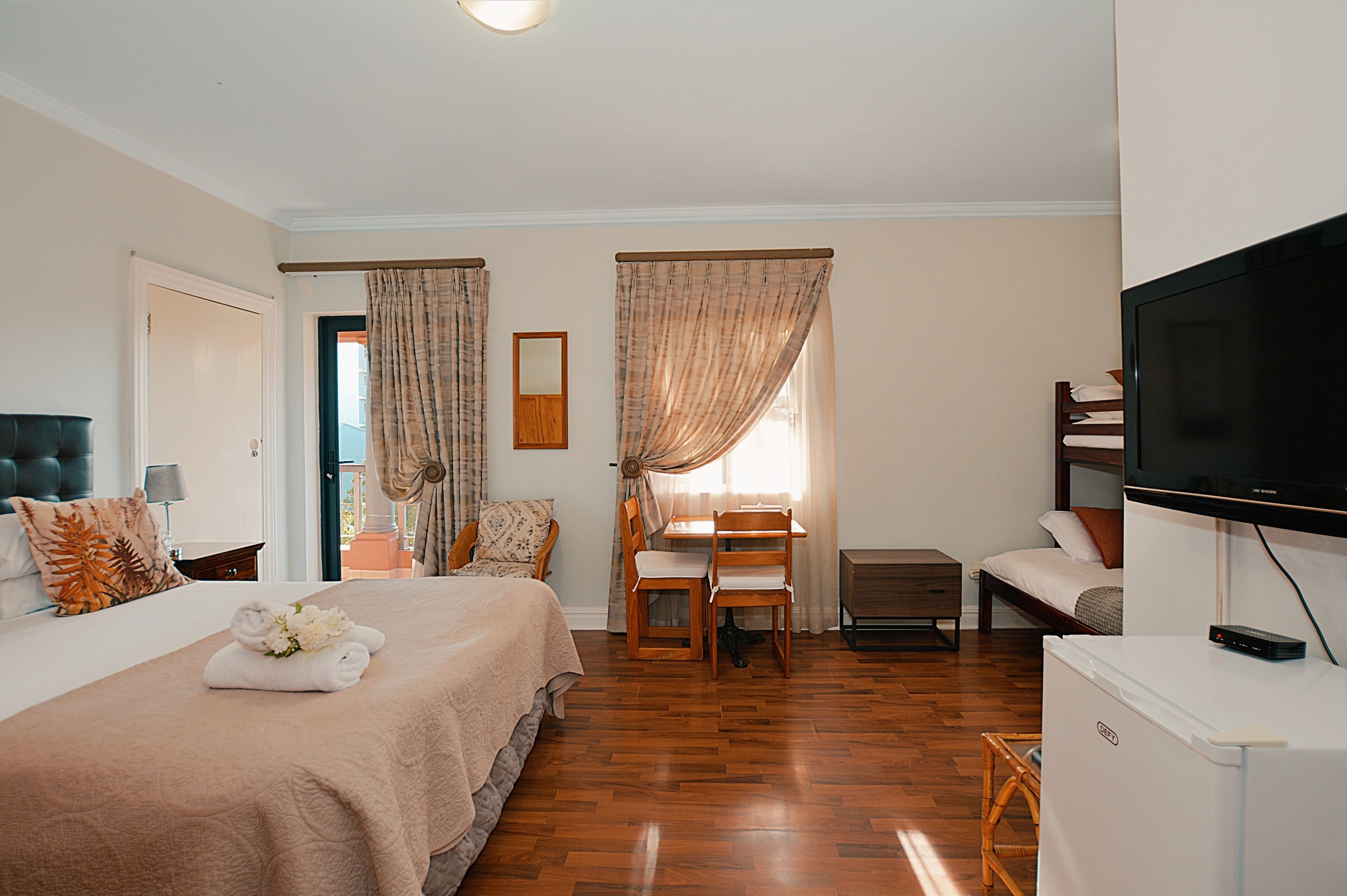 A hotel room with a bed, a desk, a chair, a television, and a refrigerator.